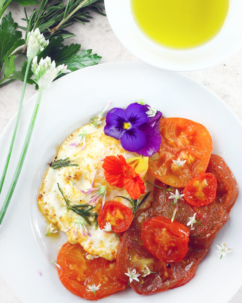 Fried eggs, fried tomatoes and edible flowers.